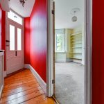 Red hallway leading to a bright room.