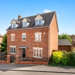 Brick house with dormer windows in suburban neighbourhood.