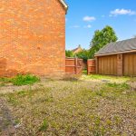 Gravel driveway with brick wall and garage.