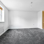 Empty room with grey carpet and large window.
