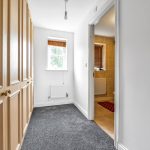 Hallway with wooden wardrobes, window, and open door.