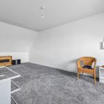 Spacious white-walled attic room with various furniture