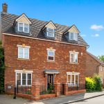 Three-storey brick house with black door and windows.