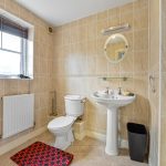 Modern bathroom with sink, toilet, and tiled walls.