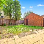 Spacious backyard with brick shed and trees.