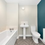 Modern bathroom with blue accent wall and bathtub.