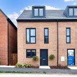 Modern brick house with for sale sign.