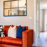Modern living room with orange sofa and dining area.