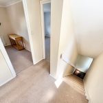 Carpeted hallway with stairs and rooms.