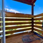 Wooden balcony with garden view on sunny day.