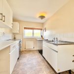 Bright kitchen with white cabinets and tiled walls.