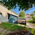 Residential garden with sheds and overgrown grass.