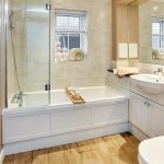 Modern bathroom with tub and wooden flooring.