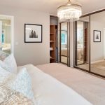 Modern bedroom with mirrored wardrobes and chandelier.