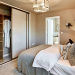 Modern bedroom with open wardrobe and soft lighting.