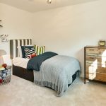 Cosy bedroom with single bed, wooden dresser.