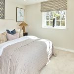 Cosy bedroom with patterned wallpaper and large window.