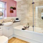 Modern bathroom with pink accent wall and bathtub.