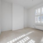 Empty bright room with window and white shutters.