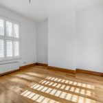 Empty room with wooden floor and white shutters.