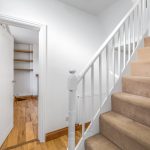 Carpeted staircase and open door with shelves.