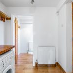 White utility room with wooden accents and washing machine.