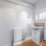 Bright bathroom with sink, toilet, radiator.
