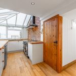 Bright kitchen with wood floors and brick wall.