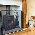 Cosy wood burner with kindling wood bucket nearby.