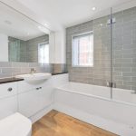 Modern bathroom with grey tiles and white fixtures.