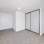 Empty room with carpet and sliding wardrobe doors.