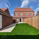 New brick house with green garden and fencing.