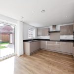 Modern kitchen with garden view through glass doors.