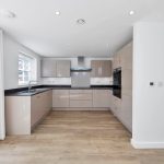 Modern kitchen with beige cabinets and wooden floor