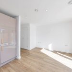 Modern kitchen with wooden flooring and light decor.