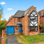 Brick house with blue garage door and autumn trees.