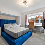 Modern bedroom with blue bed and workspace.