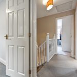 Bright hallway with carpet and doors leading to rooms.