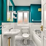 Teal bathroom with white fixtures and window view.