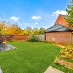 Spacious garden with autumn trees and brick house.