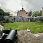 Back garden with grass, clothesline, and barbecue.
