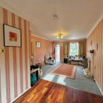 Spacious living room with striped wallpaper and hardwood floor.