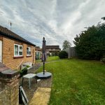 Back garden with lawn and patio furniture.