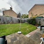 Residential backyard with lawn, patio, and rotary washing line.
