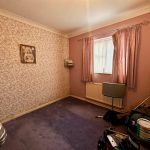 Small bedroom with pink walls and old furniture.