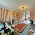 Spacious living room with striped wallpaper and fireplace.