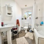 Modern bathroom with white fixtures and plants.