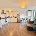 Modern kitchen and living area with wooden flooring.