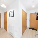 Bright hallway with wooden doors and coat rack.