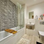 Modern bathroom with bathtub and decorative tiles.